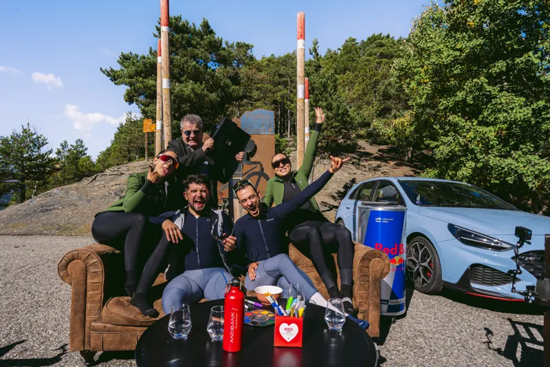 El equipo de QOM celebrando en el sofá con un coche detrás