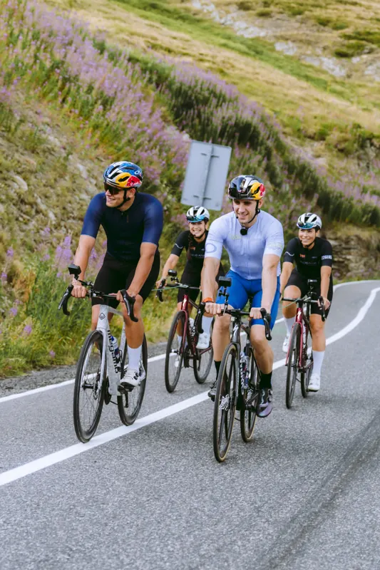 Ciclistas subiendo entre flores lilas junto a la carretera
